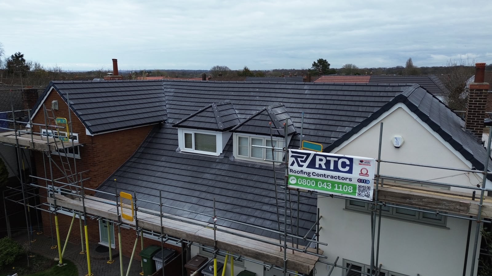Full pitched re-roof with grey concrete interlocking tiles on a Wirral semi-detached home, RTC Roofing site banner in view