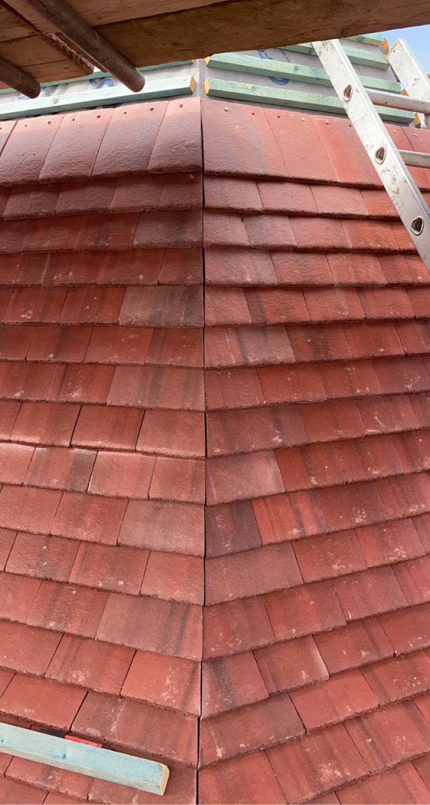 Close-up down the hip of a red clay plain tile roof showing tight tile course alignment by RTC Roofing