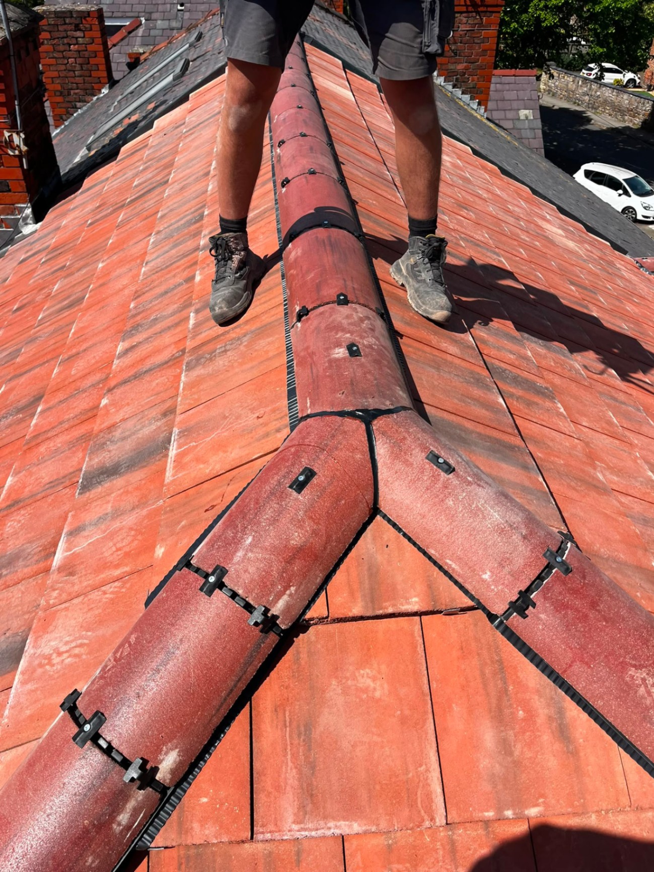 Detail of red clay hip and dry-ridge junction on a new clay tile roof by RTC Roofing
